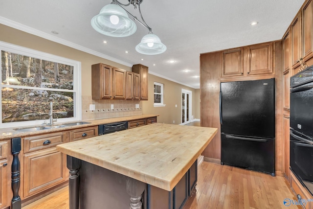 kitchen featuring a center island, sink, wood counters, light hardwood / wood-style floors, and black appliances