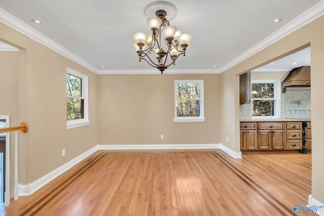 unfurnished dining area with ornamental molding, a healthy amount of sunlight, and light hardwood / wood-style floors