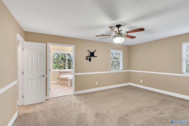 carpeted spare room featuring a textured ceiling and ceiling fan