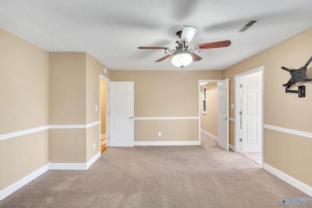 carpeted spare room with ceiling fan and a textured ceiling