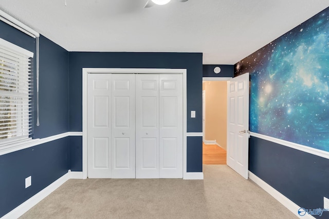 unfurnished bedroom with light carpet, a closet, and ceiling fan