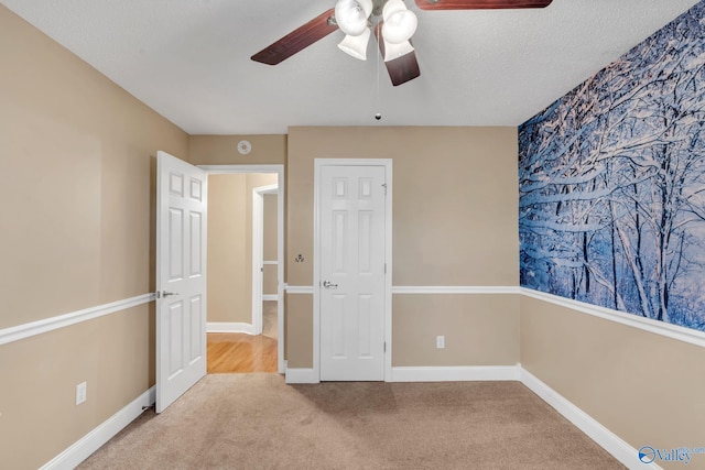 unfurnished bedroom with a textured ceiling, ceiling fan, and carpet