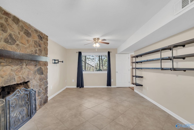 unfurnished living room featuring a stone fireplace and ceiling fan