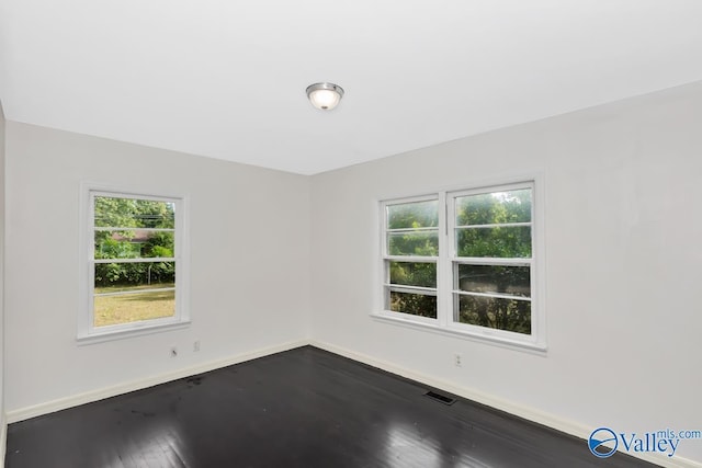 unfurnished room with visible vents, baseboards, and dark wood-type flooring