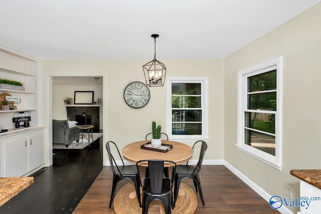 dining room with plenty of natural light, an inviting chandelier, dark wood finished floors, and a fireplace