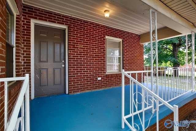 entrance to property featuring brick siding and a porch