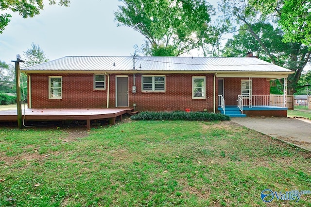 view of front facade featuring a front lawn, covered porch, brick siding, and metal roof