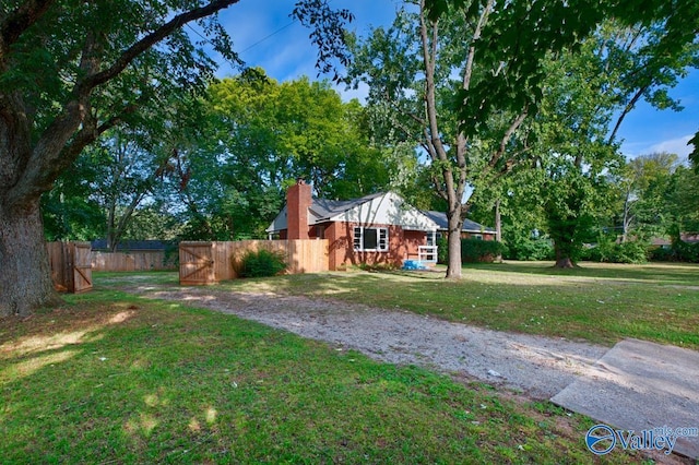 view of front facade with a front yard, a chimney, and fence