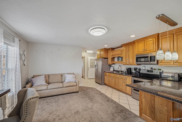 kitchen with stainless steel appliances, sink, light tile patterned floors, dark stone countertops, and hanging light fixtures