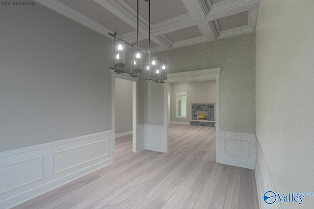 unfurnished dining area with crown molding, light hardwood / wood-style flooring, coffered ceiling, and a stone fireplace