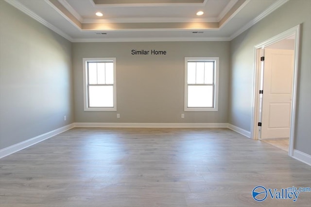 unfurnished room with a raised ceiling, crown molding, and light hardwood / wood-style floors