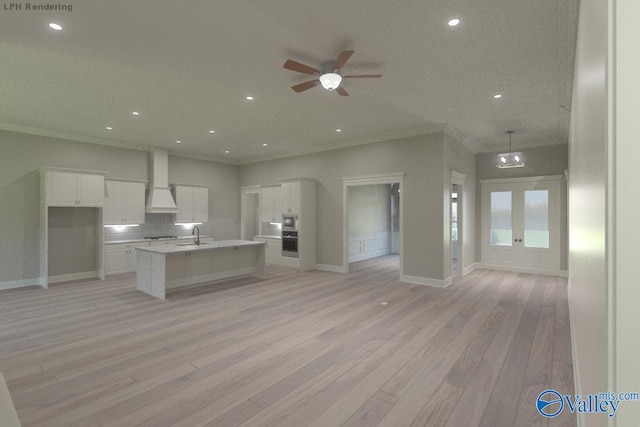 kitchen featuring white cabinets, wall chimney exhaust hood, an island with sink, and light hardwood / wood-style flooring