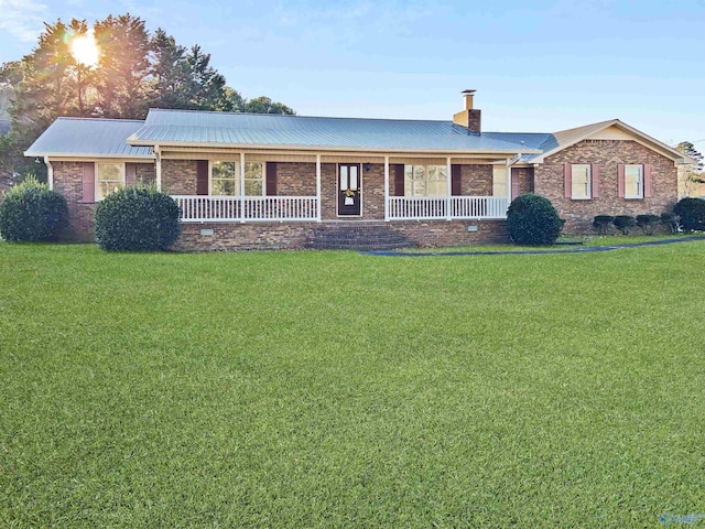 ranch-style house featuring covered porch and a front yard