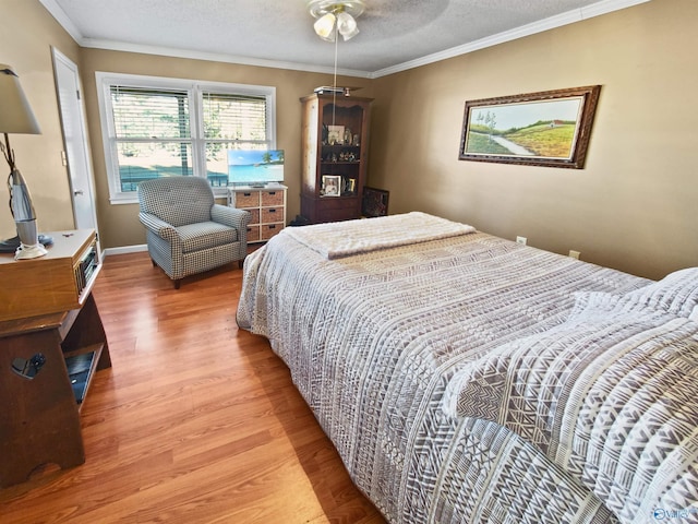 bedroom featuring ceiling fan, wood-type flooring, a textured ceiling, and ornamental molding