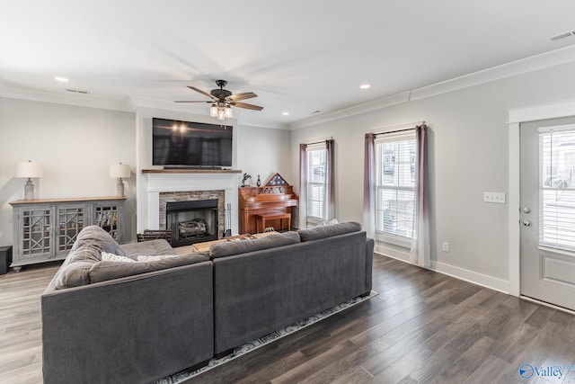 living room featuring a fireplace, hardwood / wood-style floors, ceiling fan, and crown molding