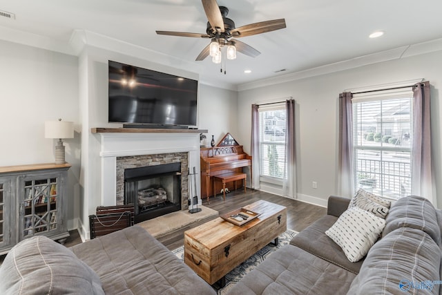 living room featuring ceiling fan, crown molding, a fireplace, and dark wood-type flooring