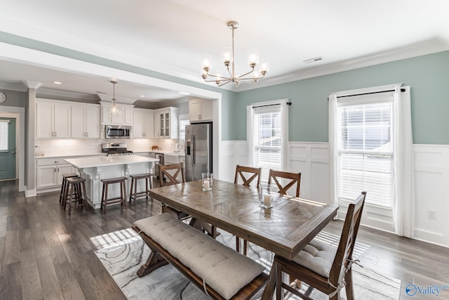 dining area featuring ornamental molding, dark wood-type flooring, and a notable chandelier