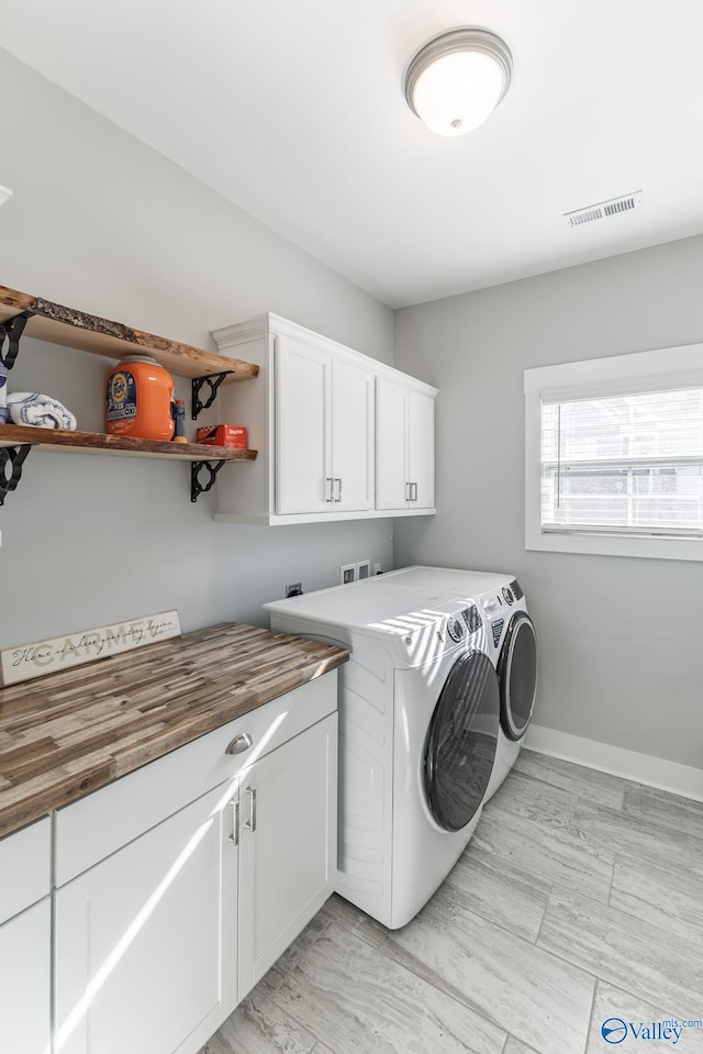 laundry area featuring separate washer and dryer and cabinets