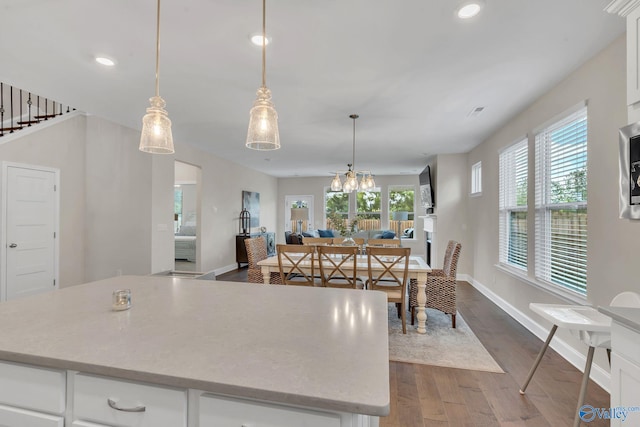 kitchen featuring pendant lighting, wood-type flooring, white cabinets, a center island, and an inviting chandelier