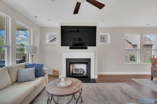 living room with dark wood-type flooring, a wealth of natural light, and ceiling fan