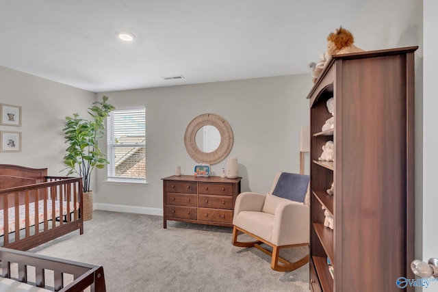 carpeted bedroom featuring a nursery area