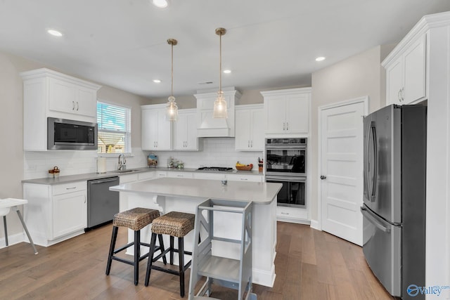 kitchen with sink, a kitchen island, white cabinets, and appliances with stainless steel finishes