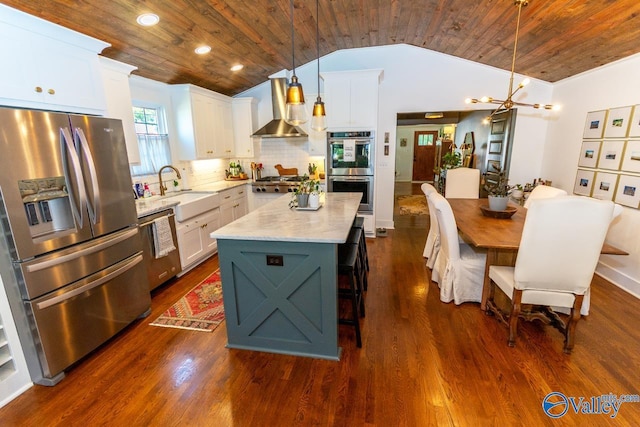 kitchen featuring stainless steel appliances, wall chimney range hood, pendant lighting, a kitchen island, and wood ceiling