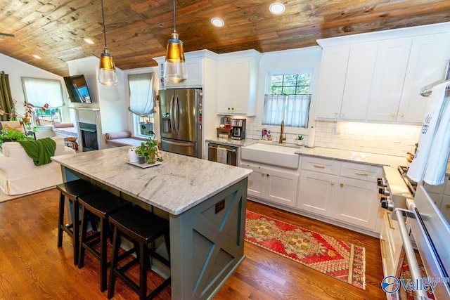 kitchen with white cabinets, a center island, sink, and stainless steel appliances