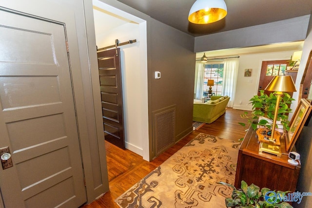 corridor with hardwood / wood-style floors and a barn door