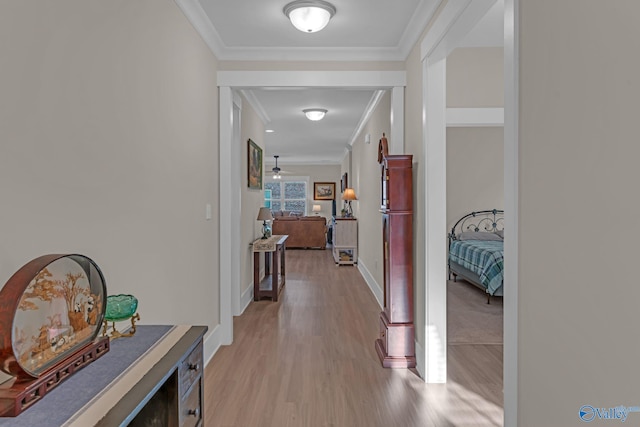 hall with light wood-type flooring and ornamental molding