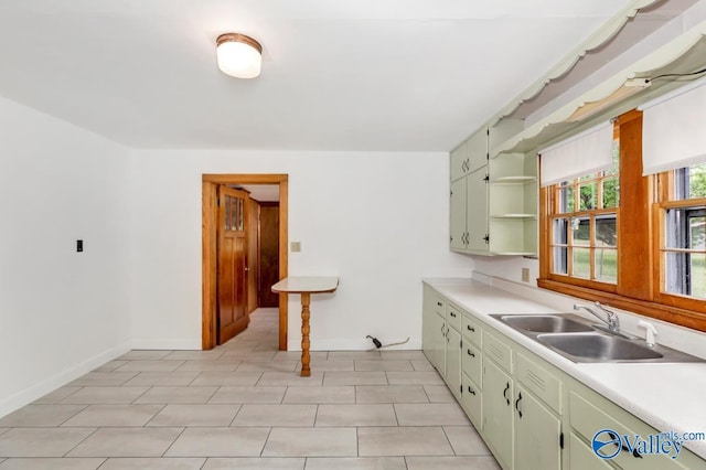 kitchen with open shelves, light countertops, baseboards, and a sink