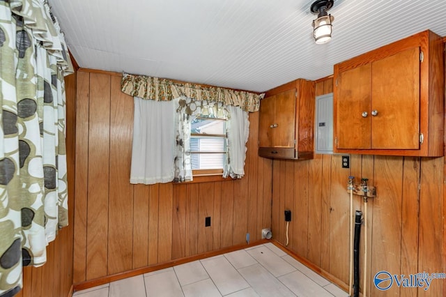 laundry room with electric panel and wood walls