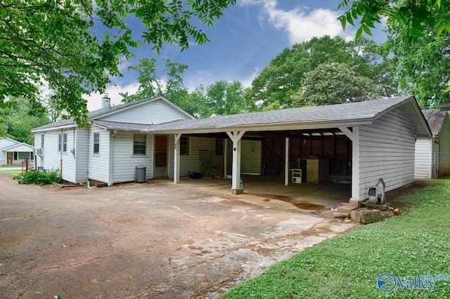 ranch-style house with a carport, driveway, a chimney, and roof with shingles