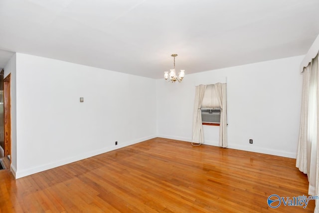 empty room featuring light wood finished floors, baseboards, and an inviting chandelier