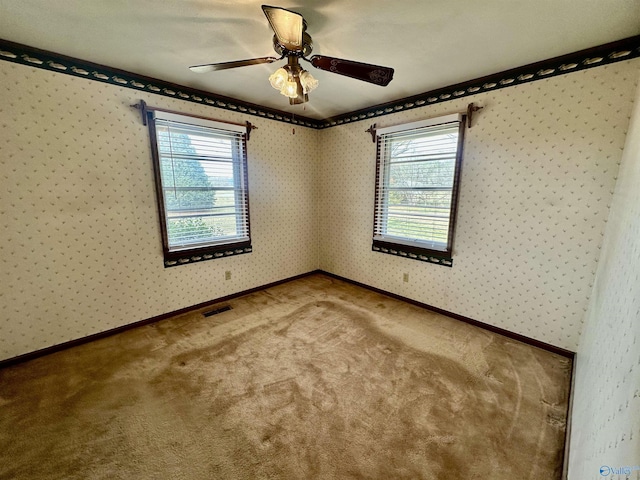 spare room featuring ceiling fan, carpet floors, and a wealth of natural light