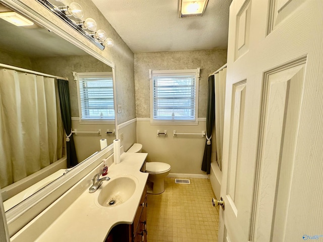 bathroom with vanity, toilet, and a textured ceiling