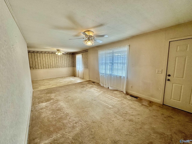 carpeted empty room featuring ceiling fan and a textured ceiling