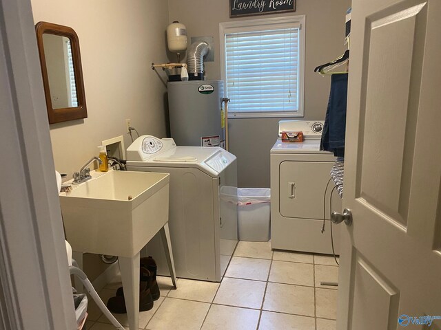 washroom featuring washing machine and clothes dryer, light tile patterned floors, and water heater