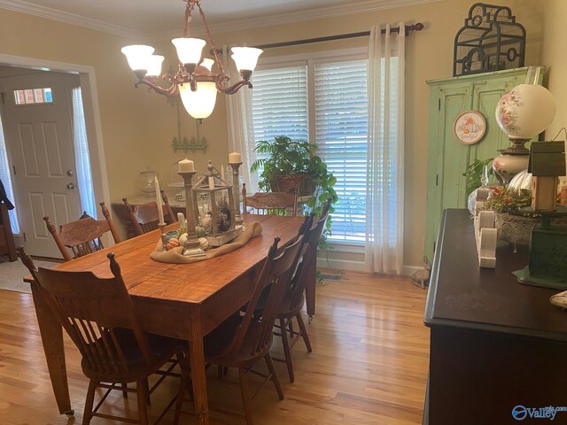 dining space with a notable chandelier, crown molding, and light wood-type flooring