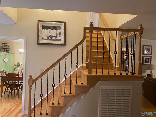 staircase with ornamental molding and hardwood / wood-style flooring