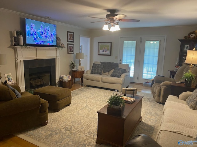 living room with a fireplace, light hardwood / wood-style floors, crown molding, and ceiling fan