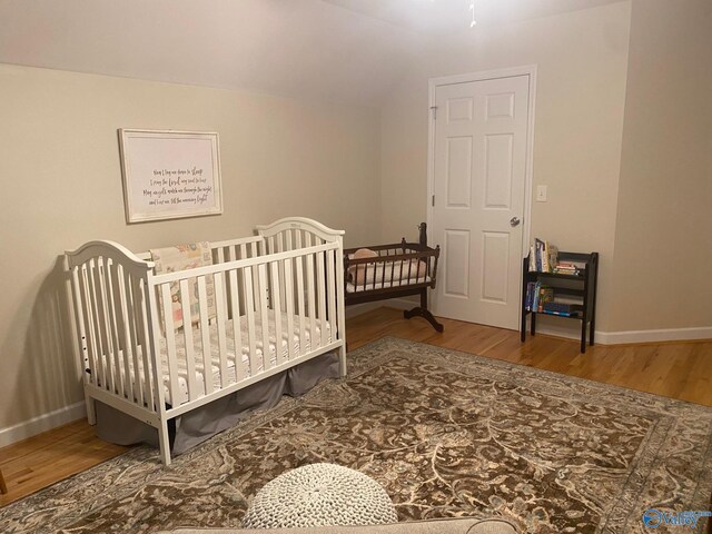 bedroom with a nursery area and hardwood / wood-style floors