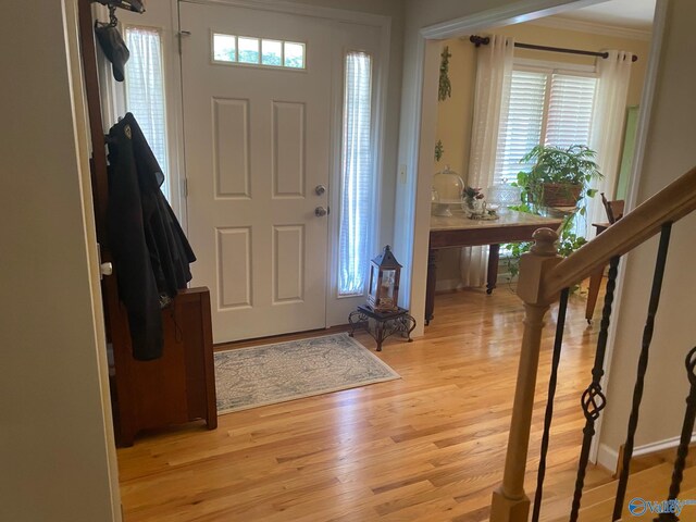 entryway with ornamental molding and light hardwood / wood-style floors