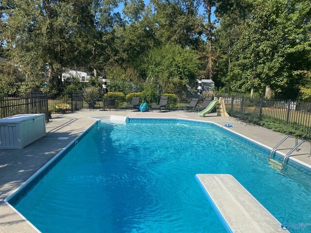 view of swimming pool featuring a water slide, a jacuzzi, and a diving board