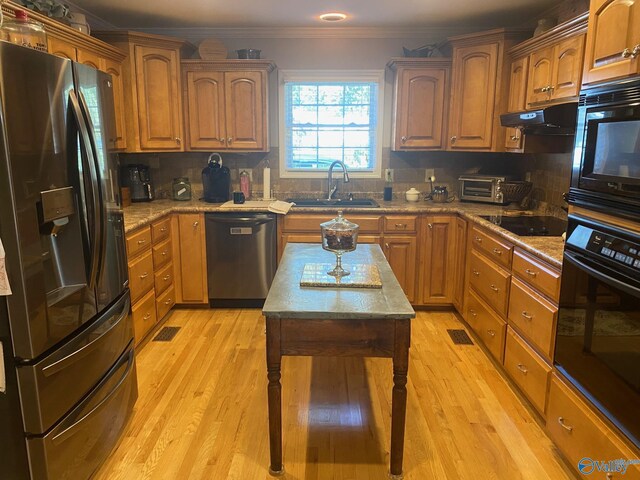 kitchen with sink, light wood-type flooring, black appliances, and backsplash