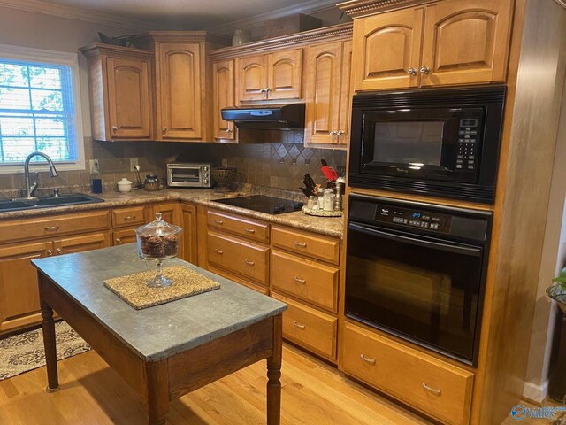 kitchen featuring range hood, black appliances, decorative backsplash, and sink