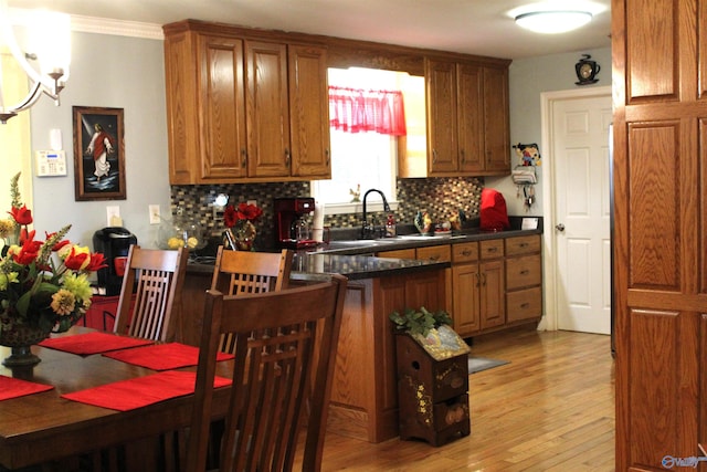 kitchen featuring sink, kitchen peninsula, decorative backsplash, light hardwood / wood-style flooring, and crown molding