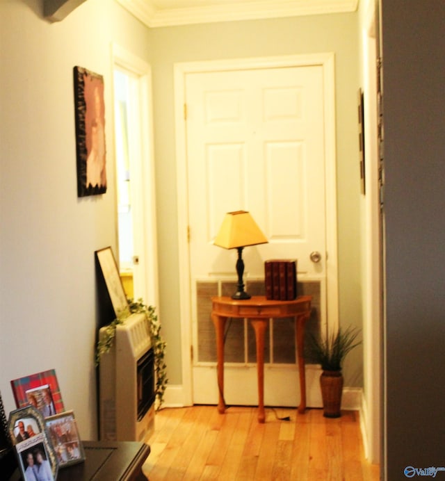 hallway featuring heating unit, light hardwood / wood-style flooring, and crown molding