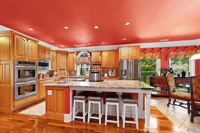 601 Smokey Mountain Cir, Huntsville, AL 35803 - kitchen featuring stainless steel appliances, a center island with sink, light stone countertops, recessed lighting, and a kitchen bar