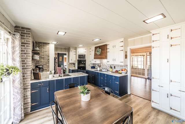 kitchen with white cabinetry, sink, black appliances, blue cabinetry, and light hardwood / wood-style flooring